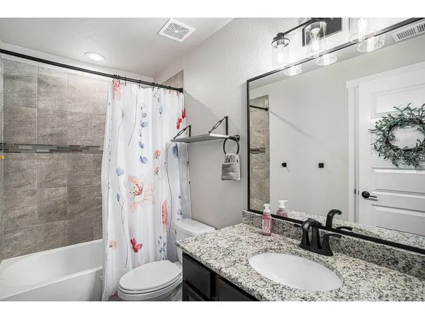 a bathroom with a granite countertop shower a sink and a mirror