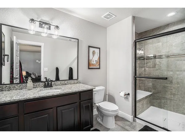 a bathroom with a granite countertop sink mirror vanity and toilet