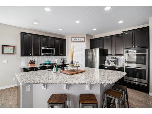 a kitchen with kitchen island granite countertop stainless steel appliances a stove sink microwave and refrigerator