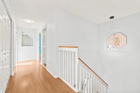 an empty room with wooden floor chandelier fan and windows