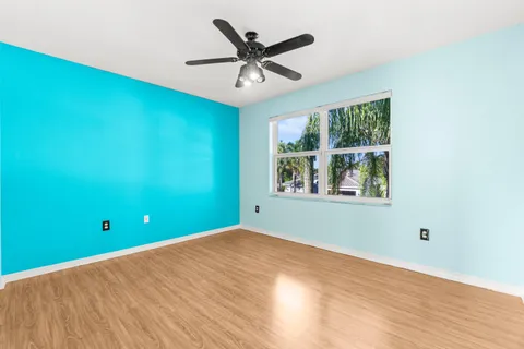 an empty room with wooden floor cabinet and windows