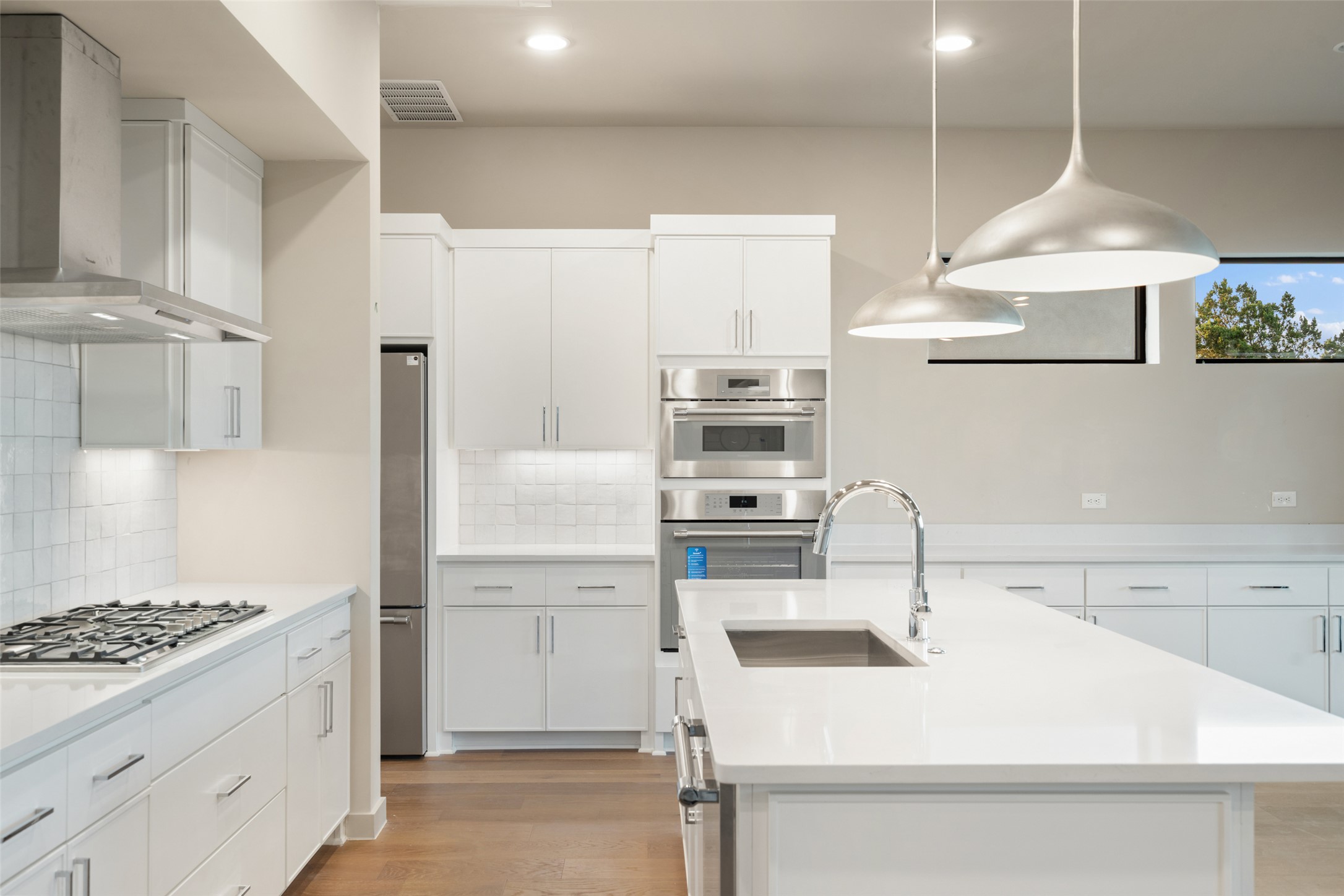 9803 Ribelin Ranch Court, Unit 16 Austin, TX 78750 - Photo 12 of 31 Streamlined cabinetry and premium built-in appliances anchor this bright culinary space with hardwood flooring.