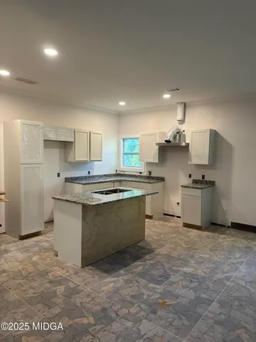 a kitchen with stainless steel appliances granite countertop a sink a stove a refrigerator and white cabinets