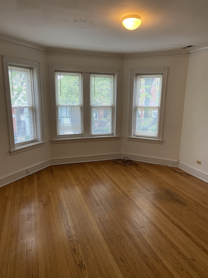 2143 West Superior Street, Unit 2F Chicago, IL 60612 - Photo 2 of 10 an empty room with wooden floor and windows