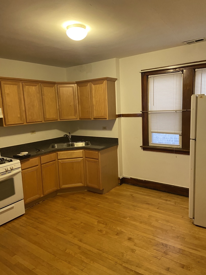 2143 West Superior Street, Unit 2F Chicago, IL 60612 - Photo 3 of 10 a kitchen with stainless steel appliances granite countertop a sink cabinets and wooden floor