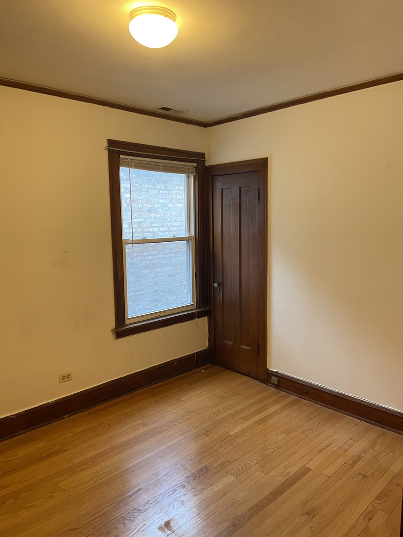 2143 West Superior Street, Unit 2F Chicago, IL 60612 - Photo 6 of 10 a view of an empty room with wooden floor and a window