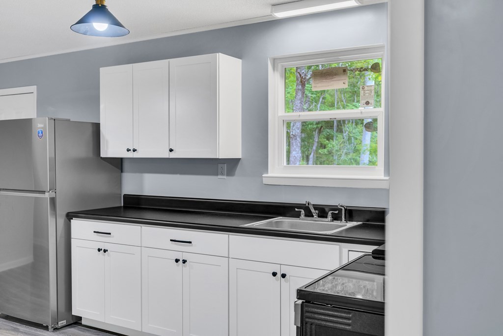 121 Twin Oaks Road Pikeville, TN 37367 - Photo 6 of 22 a kitchen with white cabinets a window and a refrigerator