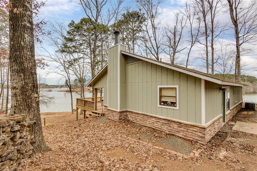 View of property exterior with a chimney, a water view, and stone siding