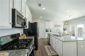 a kitchen with stainless steel appliances a sink stove refrigerator and cabinets