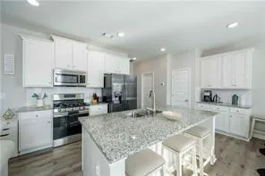a kitchen with stainless steel appliances granite countertop a stove top oven a sink and cabinets