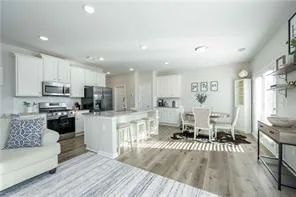 a living room with stainless steel appliances furniture and a kitchen view