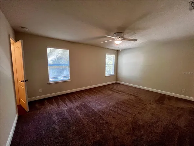 an empty room with windows and ceiling fan