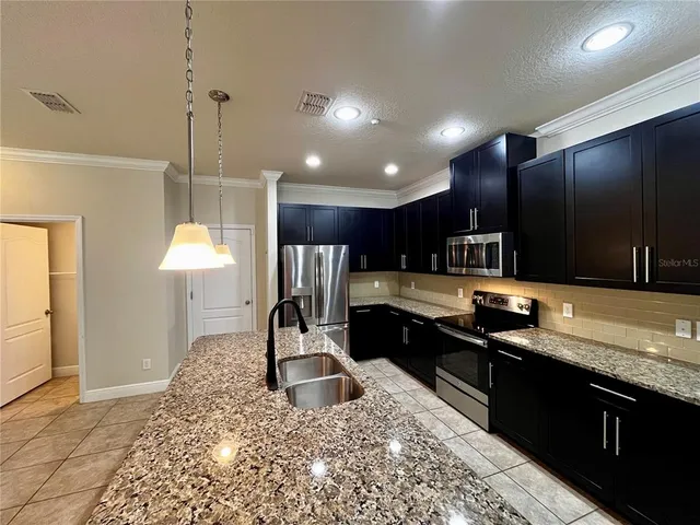 a kitchen with stainless steel appliances kitchen island granite countertop a sink a stove and a wooden floors