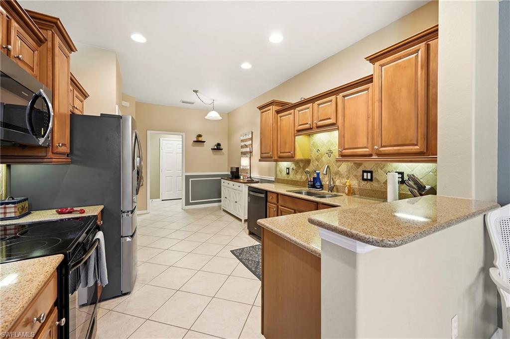 20674 Larino Loop Estero, FL 33928 - Photo 13 of 50 a kitchen that has a sink a stove and chairs
