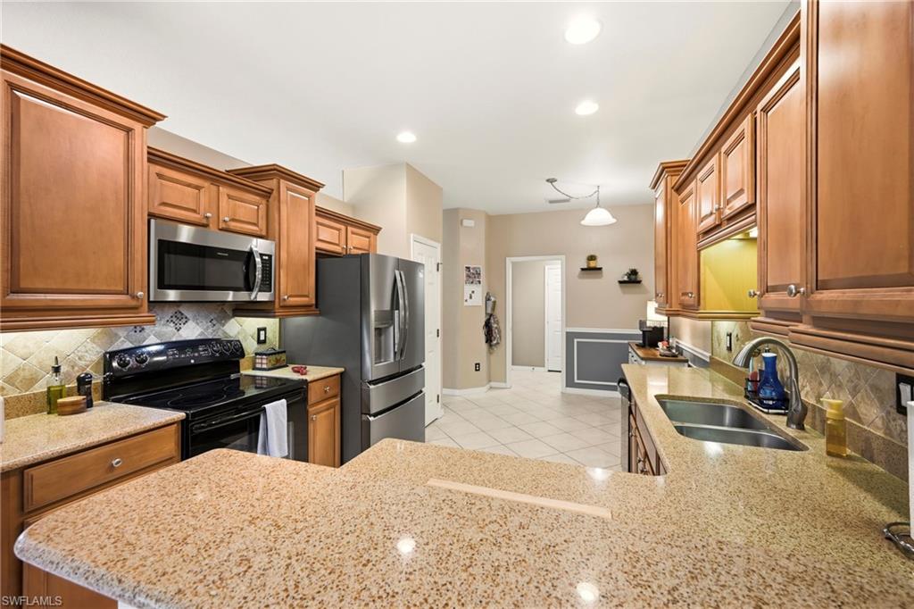 20674 Larino Loop Estero, FL 33928 - Photo 14 of 50 a kitchen with stainless steel appliances granite countertop a stove refrigerator and a sink