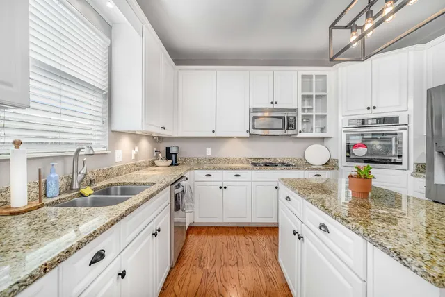 a kitchen with granite countertop a sink a stove and cabinets