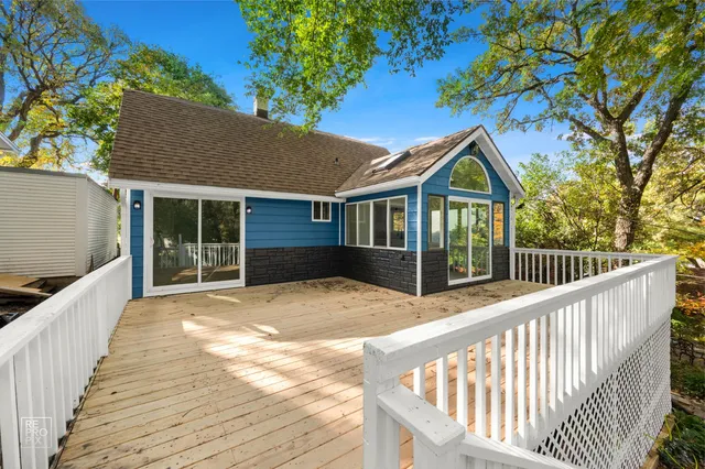 a view of a house with wooden deck and a floor to ceiling window