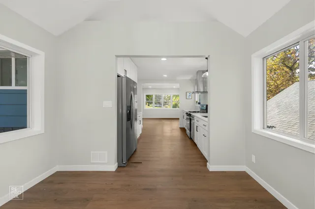 a view of a hallway with wooden floor and windows
