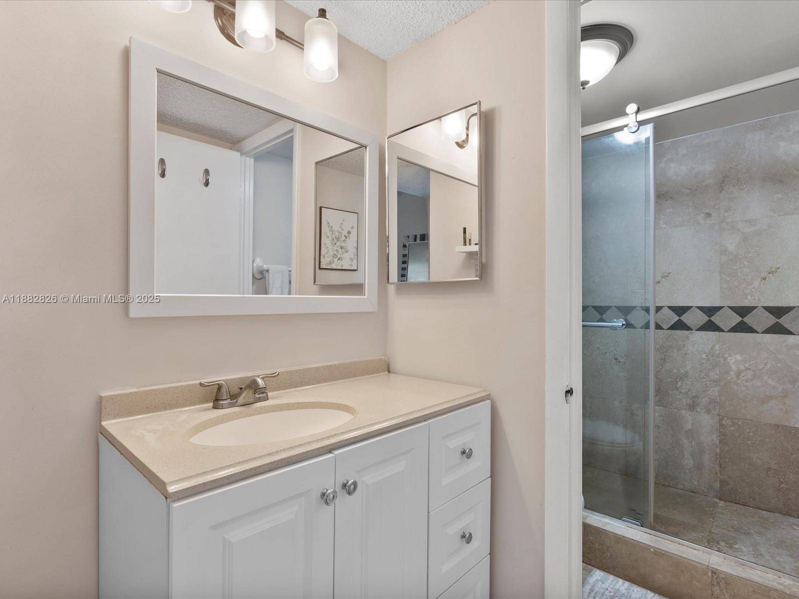 8401 West Sample Road, Unit 28 Coral Springs, FL 33065 - Photo 12 of 17 a bathroom with a sink mirror and shower