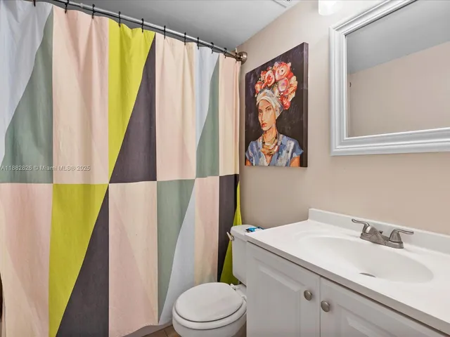 a bathroom with a sink a toilet and a shower curtain