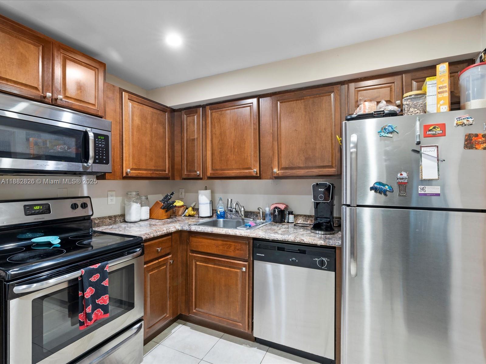 8401 West Sample Road, Unit 28 Coral Springs, FL 33065 - Photo 5 of 17 a kitchen with stainless steel appliances granite countertop a refrigerator stove top oven a sink and dishwasher