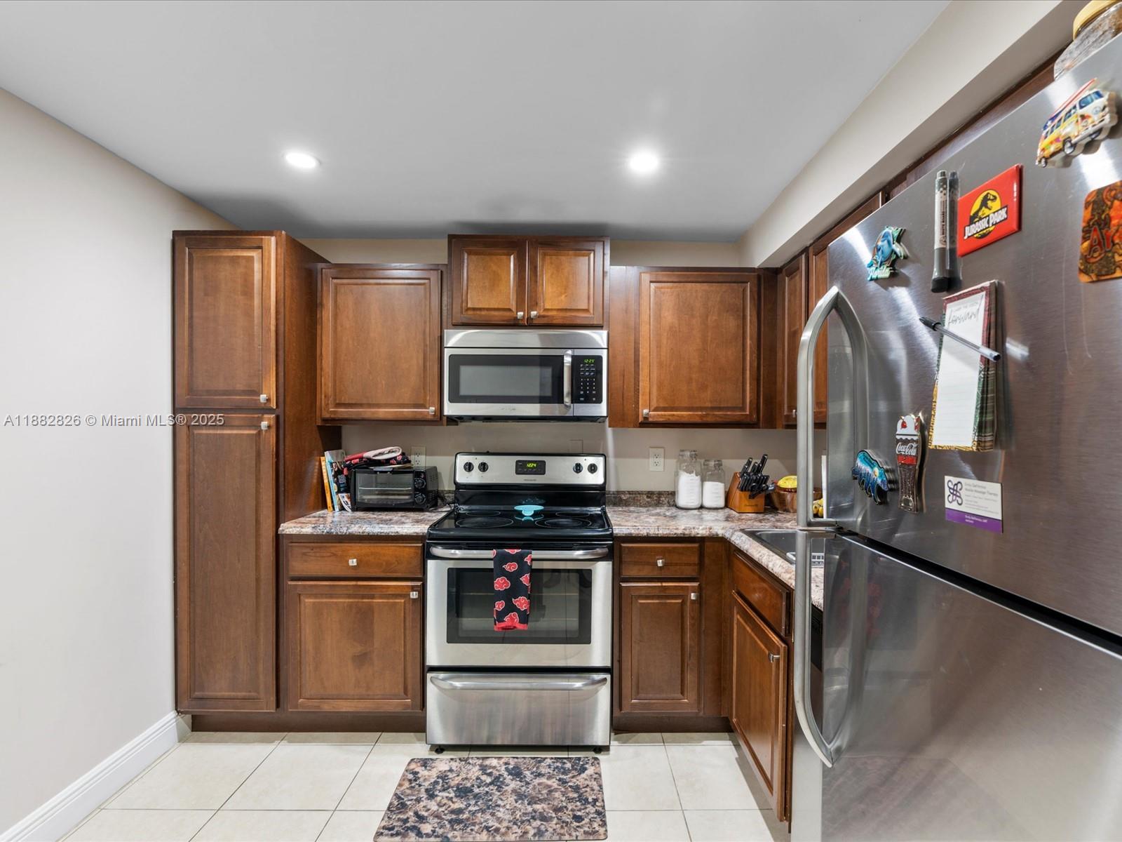 8401 West Sample Road, Unit 28 Coral Springs, FL 33065 - Photo 6 of 17 a kitchen with stainless steel appliances granite countertop a stove a sink and a microwave