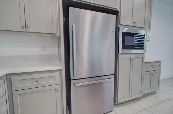 a view of a refrigerator in kitchen and white cabinets