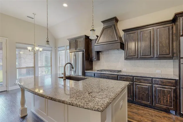 a kitchen with stainless steel appliances granite countertop a stove a sink and a refrigerator