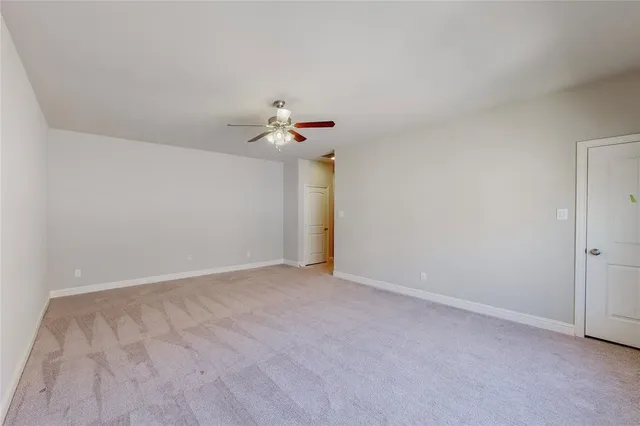 a view of an empty room and chandelier fan