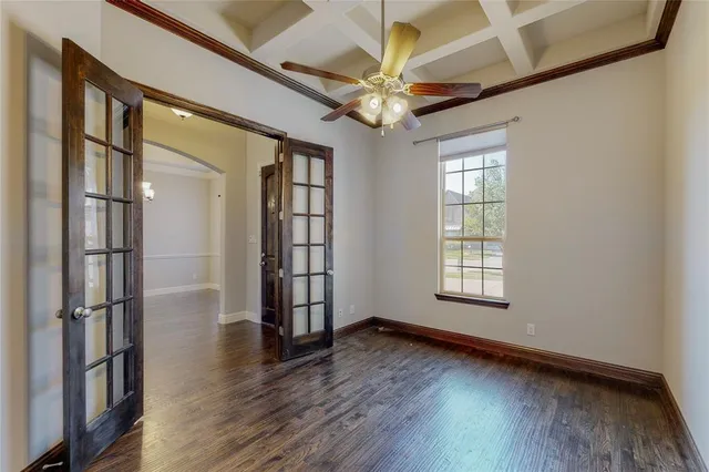 an empty room with wooden floor fan and windows