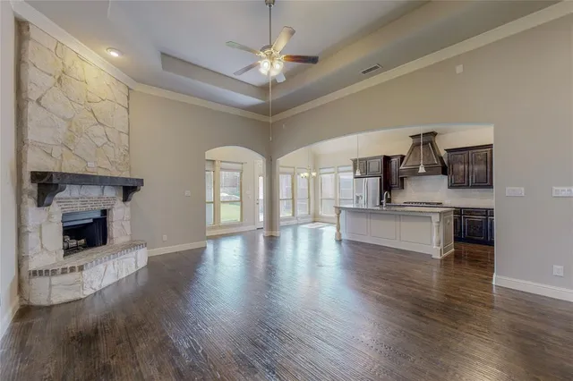 a view of an empty room and kitchen with fireplace wooden floor