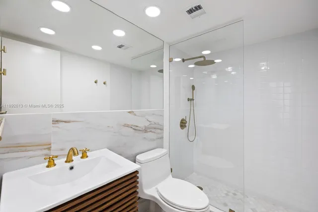 a bathroom with a granite countertop bathtub shower sink vanity and toilet