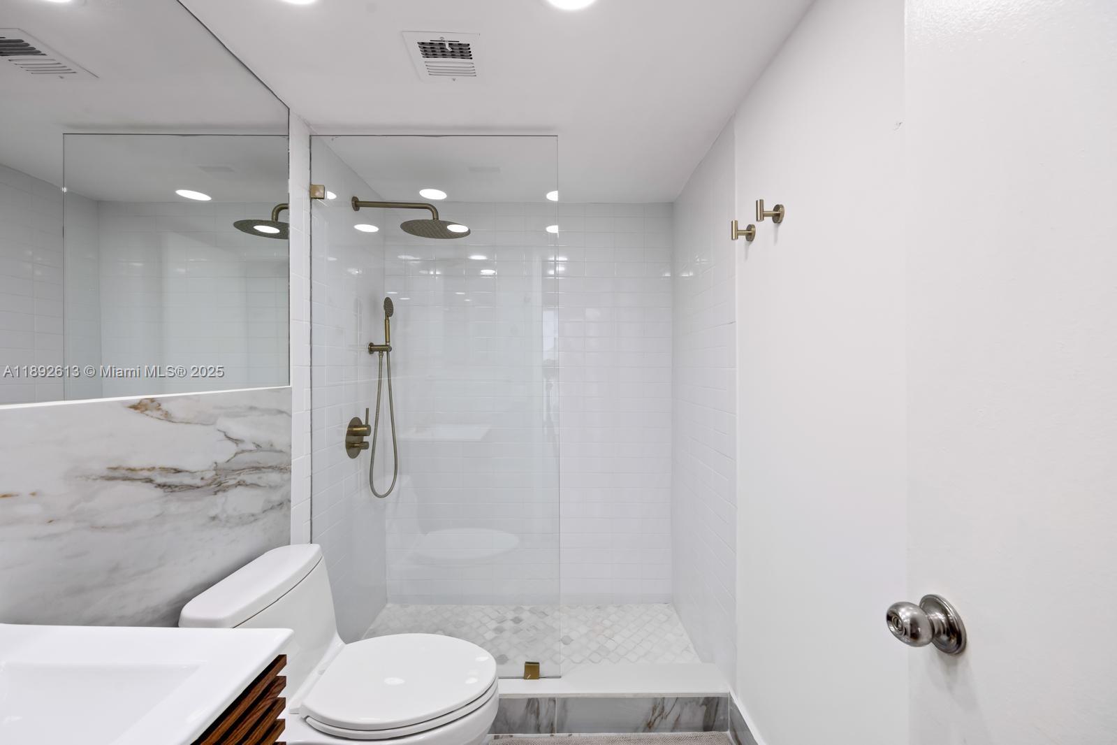 1440 Brickell Bay Drive, Unit 307 Miami, FL 33131 - Photo 16 of 28 a bathroom with a granite countertop bathtub shower sink vanity and toilet