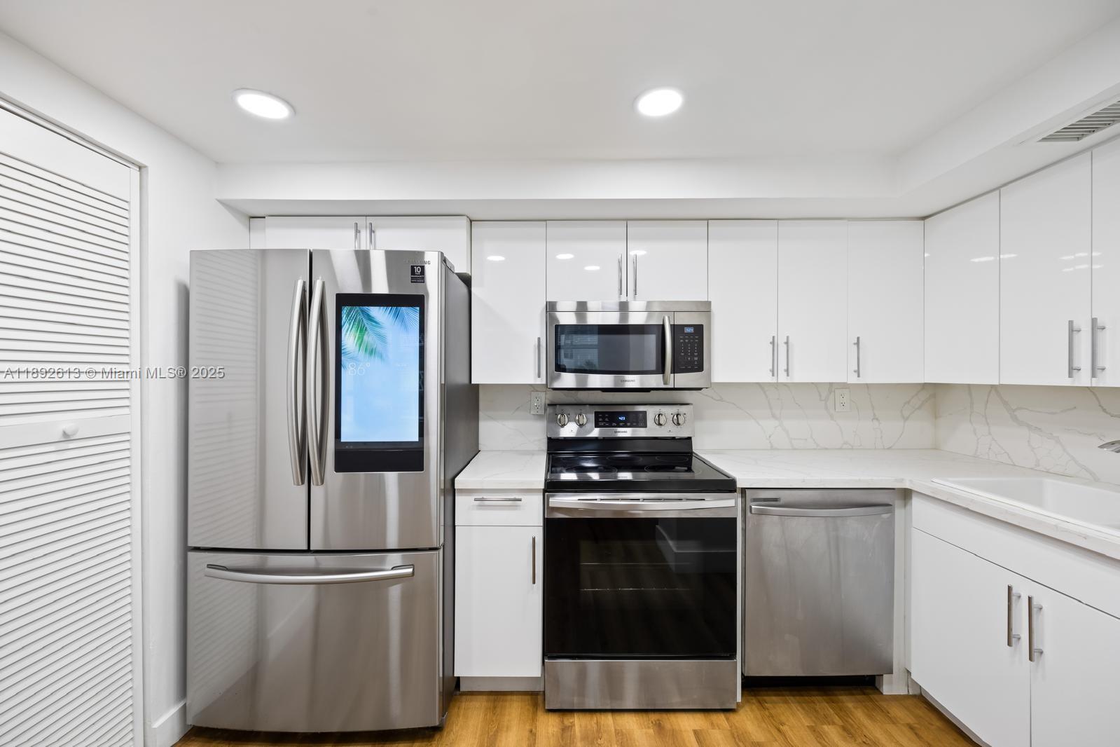 1440 Brickell Bay Drive, Unit 307 Miami, FL 33131 - Photo 10 of 28 a kitchen with cabinets stainless steel appliances and wooden floor