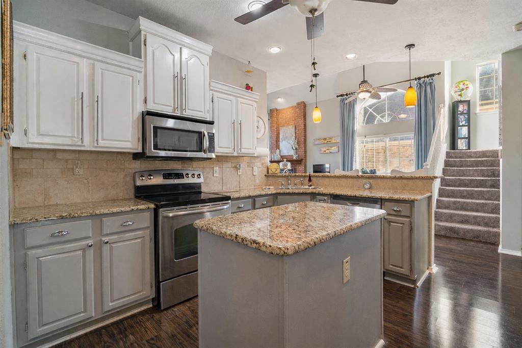 409 Red River Trail Irving, TX 75063 - Photo 6 of 31 a kitchen with kitchen island granite countertop a sink stove and wooden cabinets