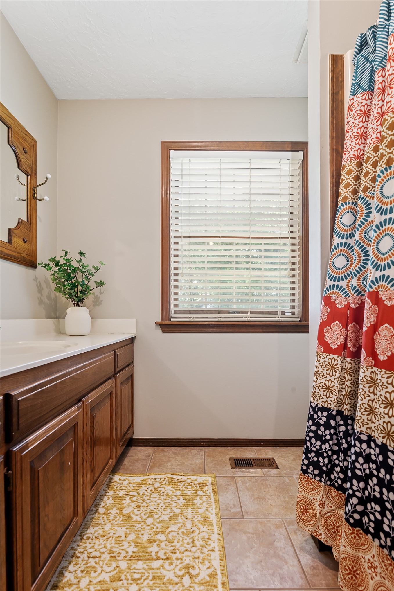 9644 19th Road Nowata, OK 74048 - Photo 29 of 36 Bathroom featuring a wood-finish vanity with a light-toned countertop, tile flooring, and a window with horizontal blinds