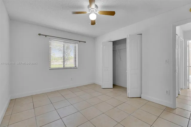 a view of an empty room with a ceiling fan and window