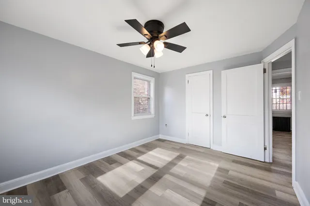 a view of empty room with wooden floor and ceiling fan