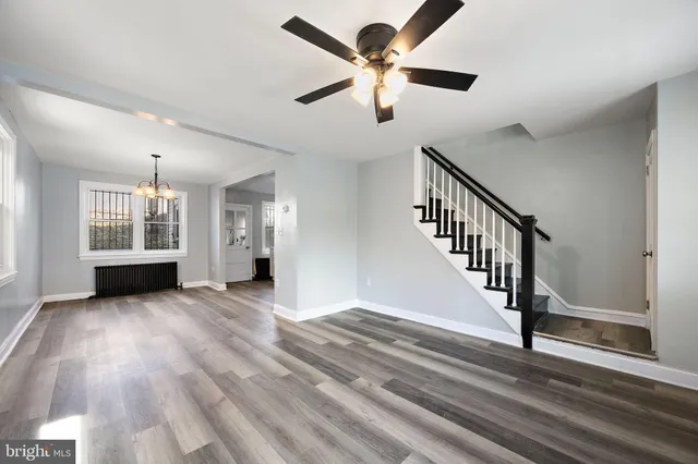 a view of an empty room with wooden floor and a ceiling fan