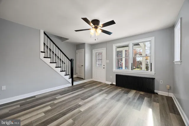a view of an empty room with window and wooden floor