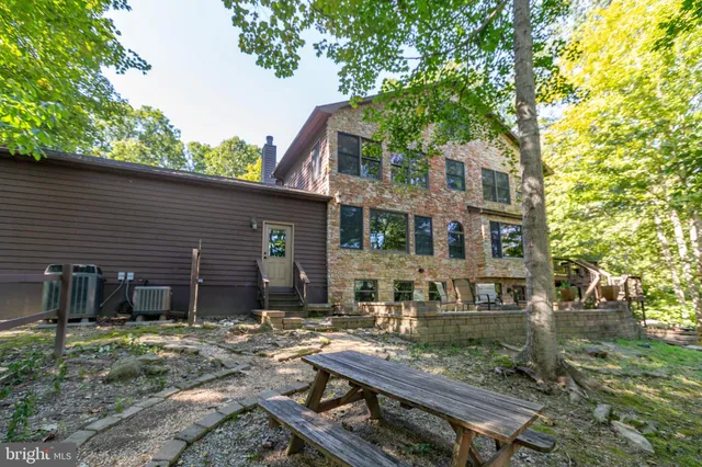 a kitchen with stainless steel appliances granite countertop a refrigerator a sink dishwasher a stove and a dining table with wooden floor