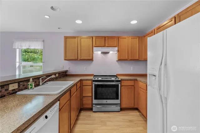 a kitchen with stainless steel appliances granite countertop a refrigerator a sink dishwasher with a dining table and chair