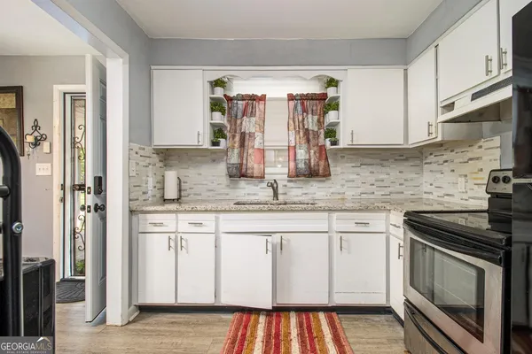a kitchen with stainless steel appliances granite countertop a stove a sink and white cabinets