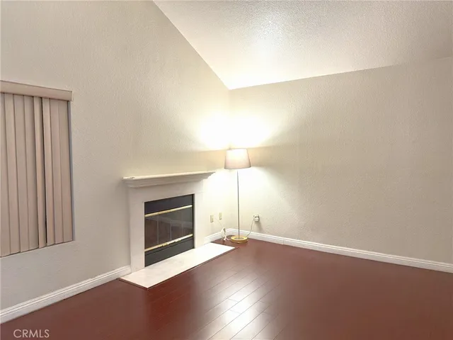 a view of empty room with wooden floor and fireplace