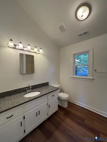 a bathroom with a granite countertop toilet a sink and a mirror