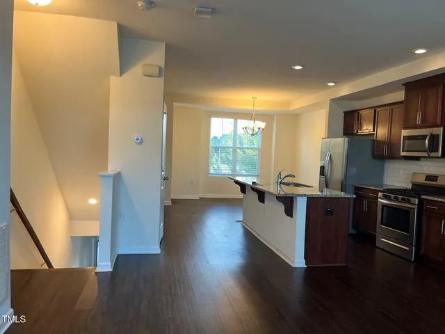 a large kitchen with a large counter top stainless steel appliances and wooden floor