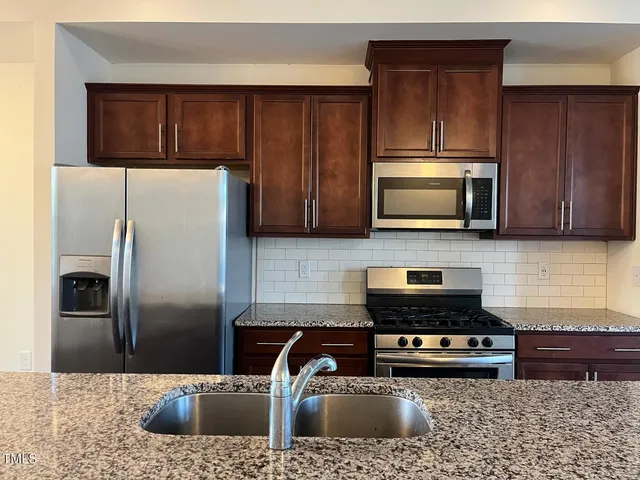 a kitchen with stainless steel appliances granite countertop a refrigerator a stove a sink and a counter space