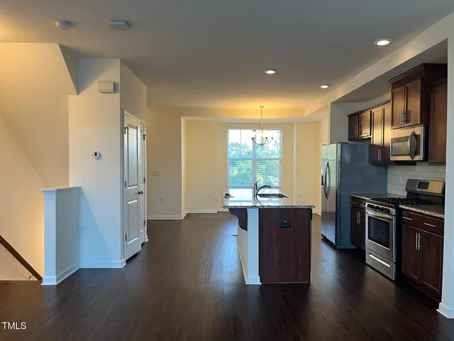 a open kitchen with wooden floor and stainless steel appliances