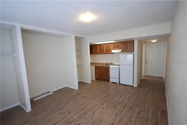 a view of a kitchen with a sink stove cabinets and empty room