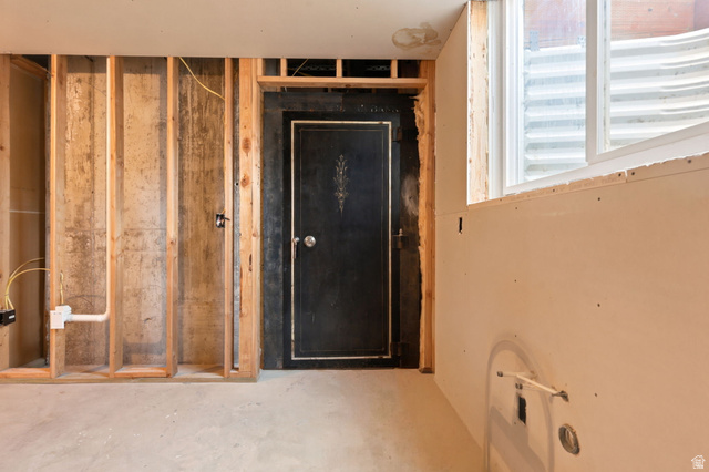 580 North 300 East Logan, UT 84321 - Photo 46 of 74 Unfinished basement space featuring a window, framed wall sections, exposed concrete foundation, and a dark, ornate built-in safe that holds nine people.